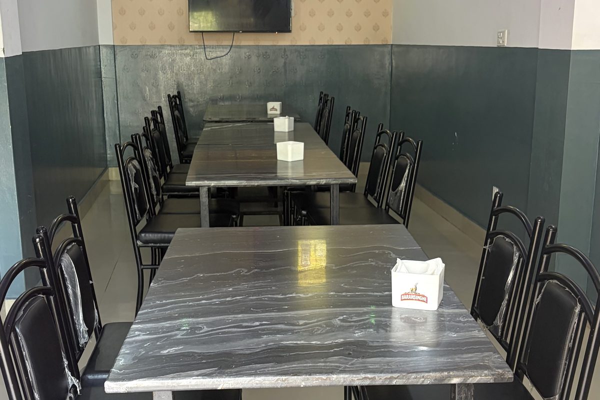 Rows of marble-top tables and chairs in the Api Hotel dining area
